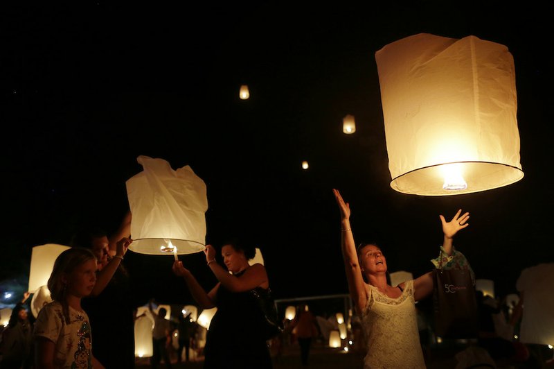 A woman releases a lantern while others light theirs, symbolizing the releasing of spirits, during a commemoration service for victims of the Asian tsunami which happened 10 years ago, Friday, Dec. 26, 2014, in Ban Nam Khem, Thailand. Dec. 26 marks the 10th anniversary of one of the deadliest natural disasters in world history: a tsunami, triggered by a earthquake off the Indonesian coast, that left more than 230,000 people dead in 14 countries and caused about $10 billion in damage. 