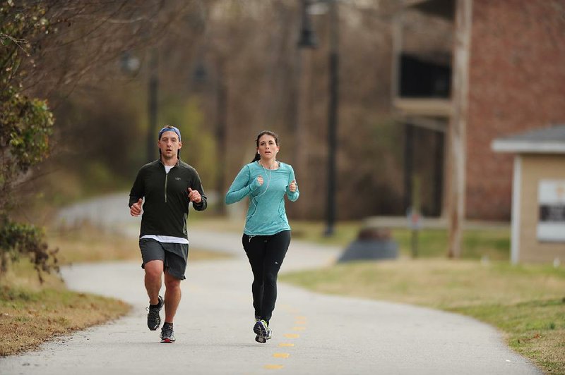 NWA Media/ANDY SHUPE - Max Mahler, left, and fiancée Lydia McCain run south on the Scull Creek Trail, a section of the Northwest Arkansas Razorback Greenway, Sunday, Dec. 21, 2014, in Fayetteville. The greenway is a regional trail system that connects Northwest Arkansas.
