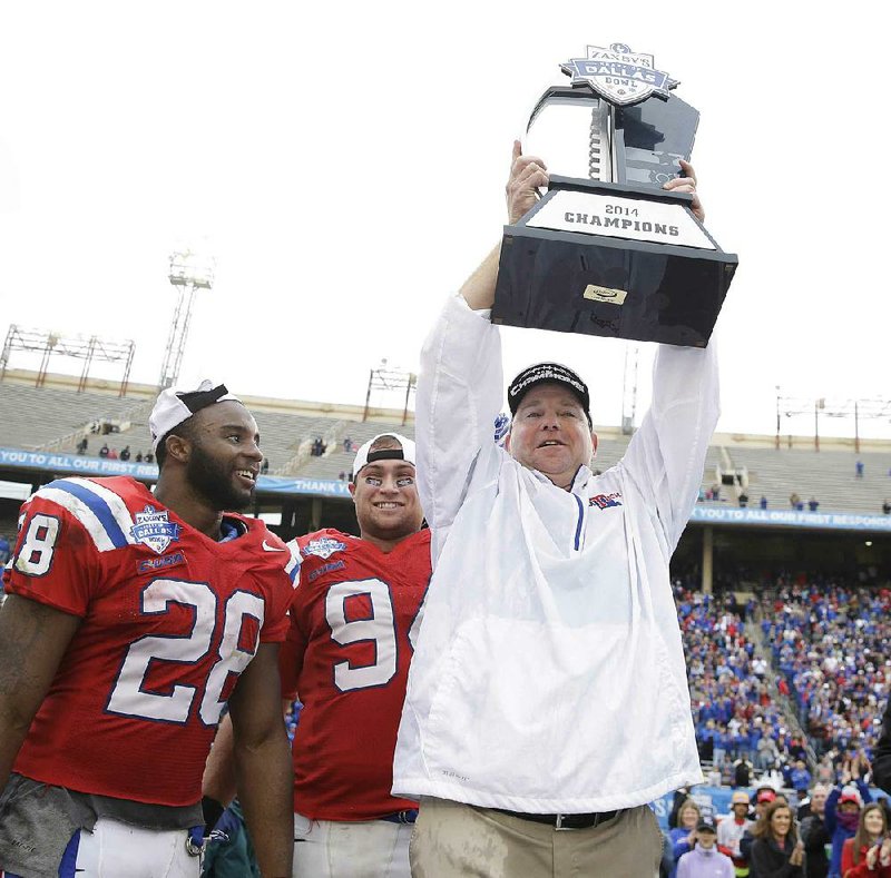 Louisiana Tech head coach Skip Holtz holds up the Heart of Dallas Bowl trophy with running back Kenneth Dixon (28) and end Houston Bates (94) looking on after the NCAA college football game against Illinois Friday, Dec. 26, 2014, in Dallas. (AP Photo/LM Otero)