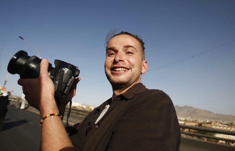 FILE - In this  Feb. 11, 2013 file photo, Luke Somers, 33, an American photojournalist who was kidnapped over a year ago by al-Qaida, poses for a picture during a parade marking the second anniversary of the revolution in Sanaa, Yemen. The body of an American photojournalist killed during a high risk raid to free him and a South African teacher from al-Qaida militants in Yemen is back on U.S. soil. The remains of Luke Somers arrived at Dover Air Force Base Wednesday aboard a U.S. Air Force C-17 aircraft. There was no public announcement. The Somers family was there to receive the remains, but no media coverage was allowed, according to a U.S. defense official who spoke on condition of anonymity because the arrival was not publicly announced.  (AP Photo/Hani Mohammed, File)