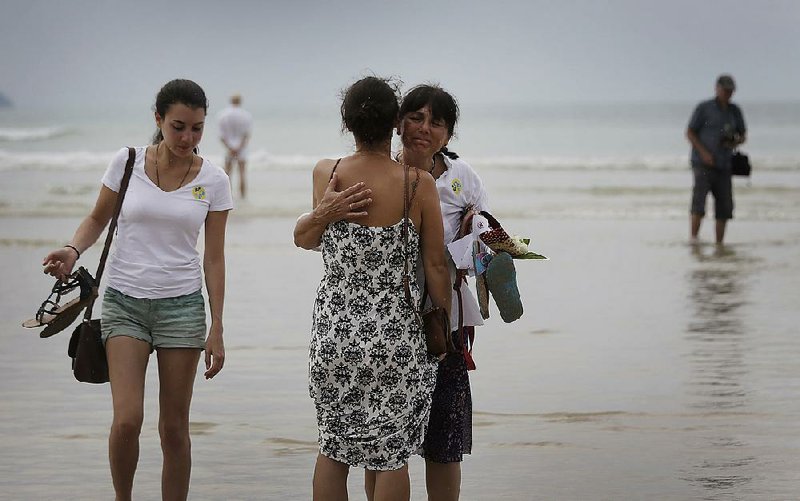 Relatives of victims of the Asian tsunami stand in the sea, some comforting each other, some reflecting quietly, while others release white roses during a commemoration and religious ceremony for German, Austrian and Swiss victims of the Asian tsunami, Friday, Dec. 26, 2014 in Khao Lak, Thailand. Dec. 26 marks the 10th anniversary of one of the deadliest natural disasters in world history: a tsunami, triggered by a massive earthquake off the Indonesian coast, that left more than 230,000 people dead in 14 countries and caused about $10 billion in damage.(AP Photo/Wong Maye-E)