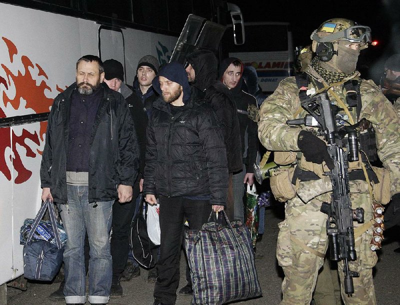 A Ukrainian soldier leads pro-Russian separatists during an exchange of prisoners outside Donetsk in eastern Ukraine, Friday Dec. 26, 2014. Ukrainian authorities and pro-Russia rebels exchanged nearly 370 prisoners Friday, the biggest one-time prisoners swap since the pro-Russian insurgency flared up in eastern Ukraine in April and a major step toward easing hostilities in eastern Ukraine. (AP Photo/Alexander Ermochenko)