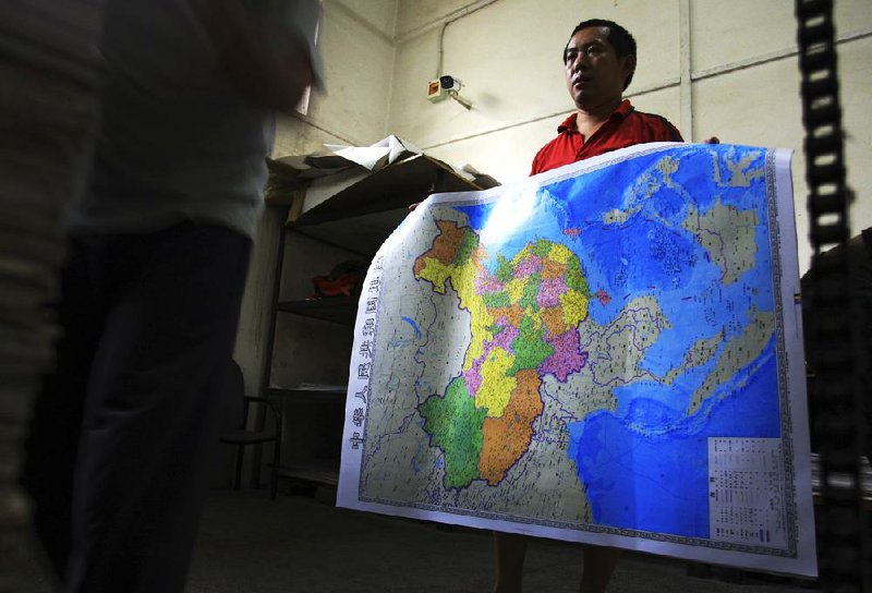 In this June 27, 2014 photo, a worker holds a new officially approved map of China that includes the islands and maritime area that Beijing claims in the South China Sea, at a printing factory in Changsha in south China's Hunan province.  China has again rejected an attempt by the Philippines to challenge its territorial claims over the South China Sea through international arbitration, releasing a lengthy paper a week before the Dec. 15, 2014 deadline for China to respond to the case. China prefers to settle its disputes with discussions with the countries directly involved. But the Philippines has filed a case with an international tribunal. (AP Photo) CHINA OUT