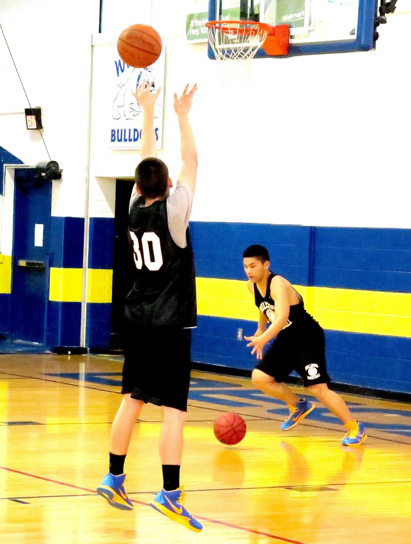 Photo by Mike Eckels During the last regular practice before the Christmas break Dec. 23, Meng Vang (lower right) recovers his basketball after a successful lay up while team mate Jay Porter (left) puts up a jumper. The Bulldogs won their conference opener Dec. 19 by defeating JC Westside at Coal Hill 49 to 32.