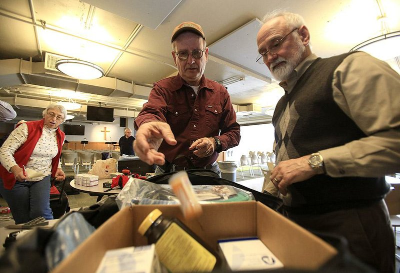 The Rev. Chris Cooper (right) and Tom Baxter (center) pack supplies Wednesday for a short-term mission trip, while Betty Cooper (left) works on another bag. The medicine, vitamins and other supplies are destined for Cuba and should arrive there Friday. 