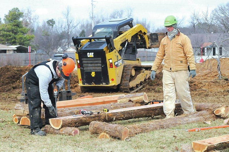 STAFF PHOTO FLIP PUTTHOFF Justin Baker, left, and Nicholas Vickers work Tuesday on log rides that will be part of the mountain bike trail at the Arkansas Arts Academy campus on South 12th Street in Rogers.