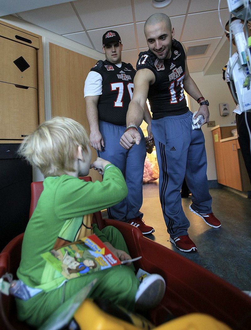 Hospital visit Arkansas State football players Austin Moreton (left) and Sterling Stowers say goodbye to Preston Jones, 3, after visiting his room Friday at the University of South Alabama Children’s and Women’s Hospital in Mobile, Ala. Players, coaches and team mascots from both Arkansas State and Toledo spent time with the children, took pictures, signed autographs and provided memorabilia and gifts from the bowl and their respective teams.