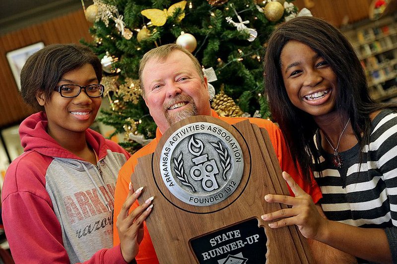 Hall High School student Jasmine Brown (left) and home-schooler Ashley Gray flank Coach Darrell Porter with their state tournament team runner-up trophy, won shortly after they formed the Little Rock high school’s tennis team.