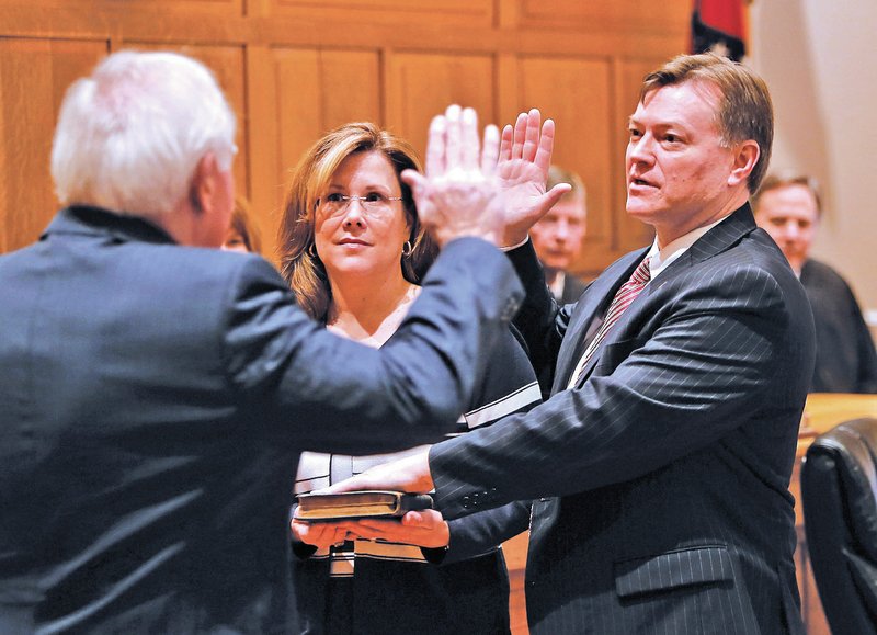 STAFF PHOTO DAVID GOTTSCHALK John Threet, from right, stands next to his wife, Joan Threet, as he is sworn in Friday as a Washington County circuit judge by Judge William Storey at the Old Washington County Courthouse in Fayetteville. Additional photographs available at nwaonline.com/photos.
