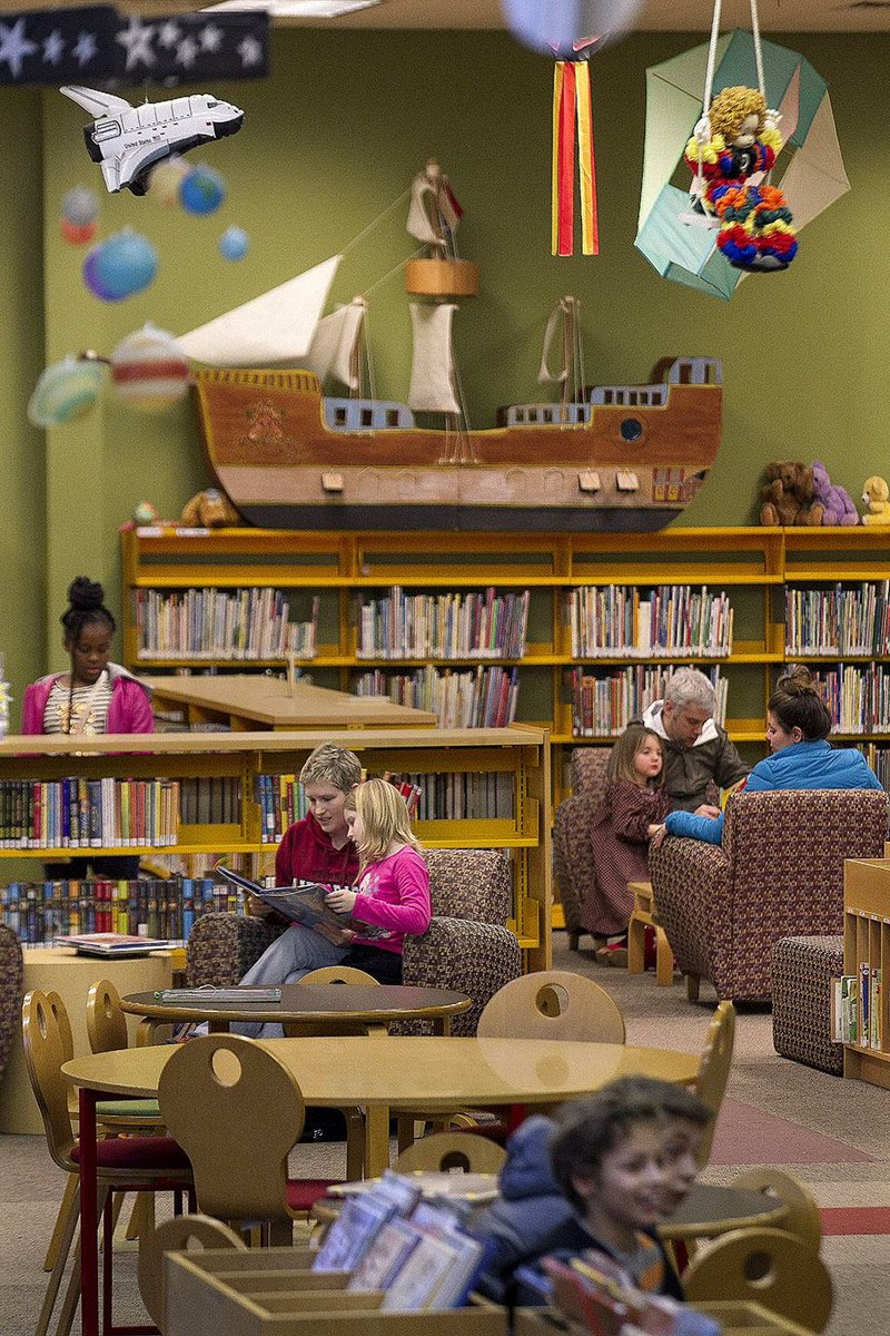 Brittany Franklin of Maumelle (center left) and her daughter, Emma, read books Saturday in the children-and-teen area of the Laman Library in North Little Rock. Budget problems have led to reduced hours and programs at the library. 