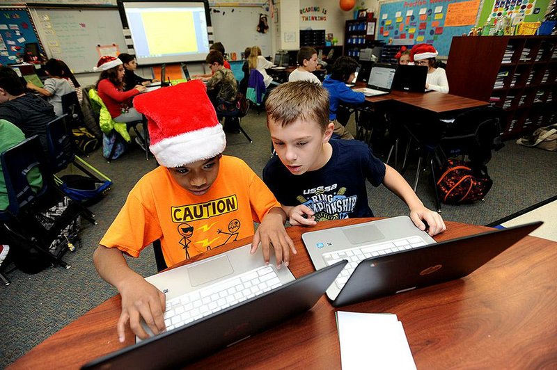 NWA Media/ANDY SHUPE - Breacher Jie, 11, left, and Tyler Ridley, 10, work on a Google Slide presentation Thursday, Dec. 18, 2014, on Chromebooks in Sharon Cain's fourth-grade class at Hunt Elementary School in Springdale. The Springdale School District has spent $7.45 million of a four-year, $25 million Race to the Top grant from the U.S. Department of Education, with $6.14 million going toward technology.