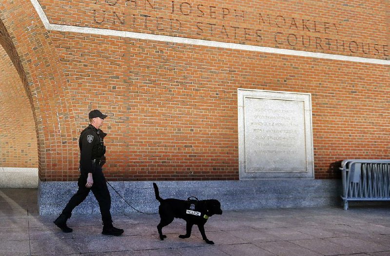 A police officer and K-9 dog patrol outside the federal courthouse in Boston, Monday, Jan. 5, 2015, on the first day of jury selection in the trial of Boston Marathon bombing suspect Dzhokhar Tsarnaev. Tsarnaev, 21, is accused of planning and carrying out the twin pressure-cooker bombings that killed three people and wounded more than 260 near the finish line of the race on April 15, 2013. (AP Photo/Elise Amendola)