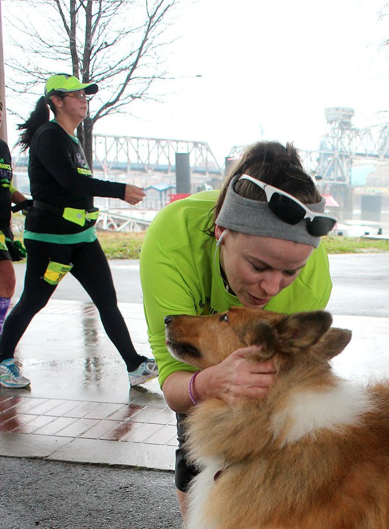 Arkansas Democrat-Gazette/CELIA STOREY
Runner Ashley Padgett of Pflugerville, Texas, takes a break Saturday during the Jacob Wells 3 Bridges Marathon to pet Kathleen Rea's dog, Luke, at the Argenta Foundation's rest stop in North LIttle Rock. Rain made the Arkansas River Trail slick Dec. 27 for 400 runners and walkers doing the Jacob Wells 3 Bridges Marathon. The second annual race is now named for its director, who died in November after collapsing during the Midsouth Championship Marathon at Wynne.