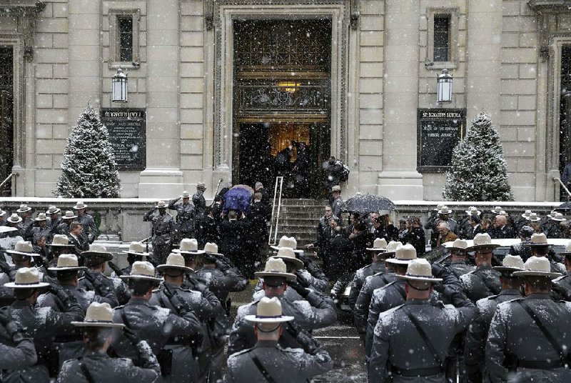 New York state Troopers salute Tuesday in Manhattan as the coffin containing the remains of former Gov. Mario Cuomo is carried into the Church of St. Ignatius Loyola. 