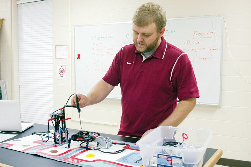 Beebe Junior High School teacher Tate Rector shows off one the robots designed by his students. The robot measures the internal temperature of a Hot Pocket.