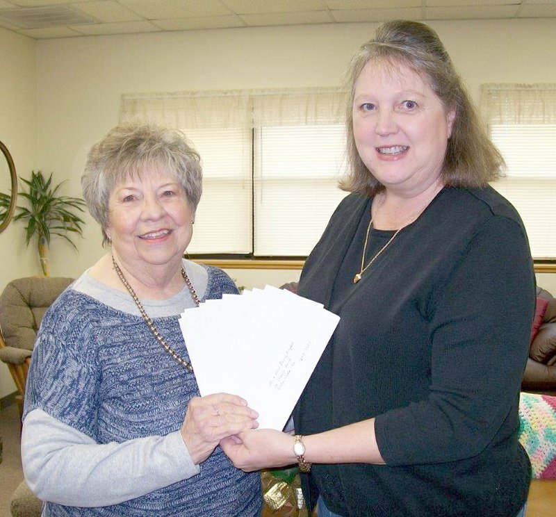 Photo by Melissa Steele Mary Kay Kelley, left, accepts checks totaling $635 from Bella Vista resident Betsy Meek. The donation was collected at the annual Mason Lane Christmas party on Dec. 13.