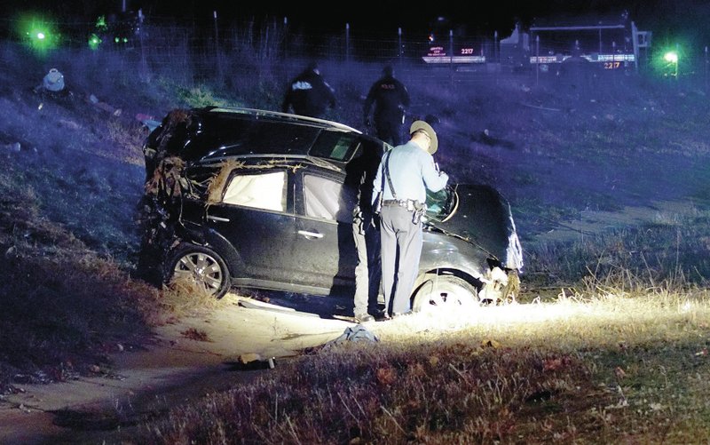 Photo by Randy Moll State police, assisted by Gentry police, investigate a single-vehicle rollover accident on Sunday night, on Arkansas Highway 59 south of Gentry, in which the driver was pinned under the vehicle.