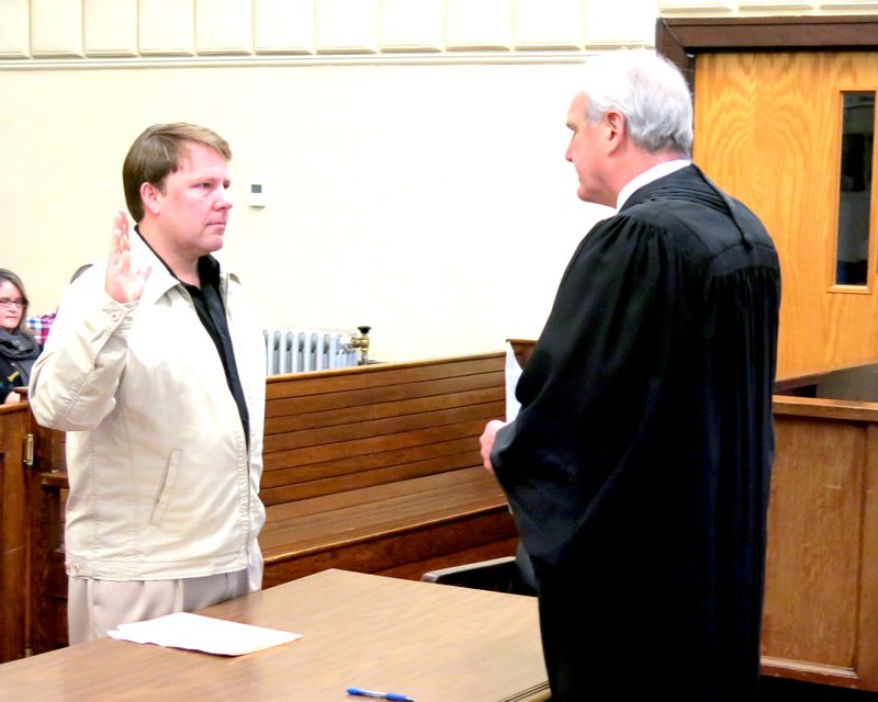 Photo by Mike Eckels Newly elected Gravette Mayor Kurt Maddox takes his oath of office from the honorable Judge Doug Schrantz Jan. 1 in the Division 1 courtroom at the Benton County Courthouse.