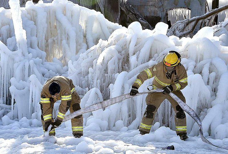 Firefighters in Springfield, Ohio, try to pull out a frozen hose Wednesday after battling an overnight five-alarm blaze that destroyed a warehouse.