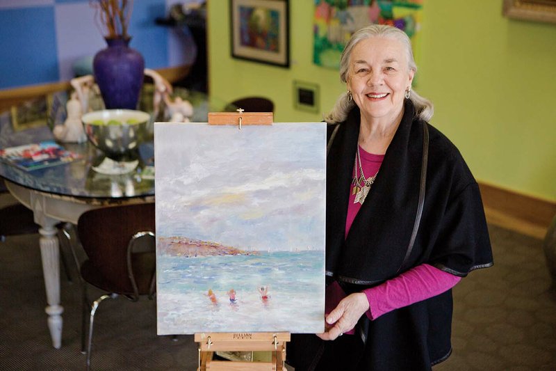 Award-winning artist Bonnie McKay of Conway stands in Art on the Green with a seascape from her newest painting series. McKay said she particularly enjoys painting landscapes ­— particularly in Arkansas — and beach scenes, both in oil and watercolor. She grew up in the Delta and often uses her memories for inspiration, she said.