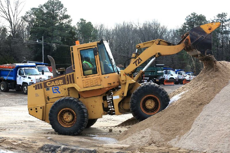 Robert West tidies up a pile of sand with a front-end loader after loading trucks Friday at the Little Rock Street Department in preparation for freezing precipitation this weekend. 