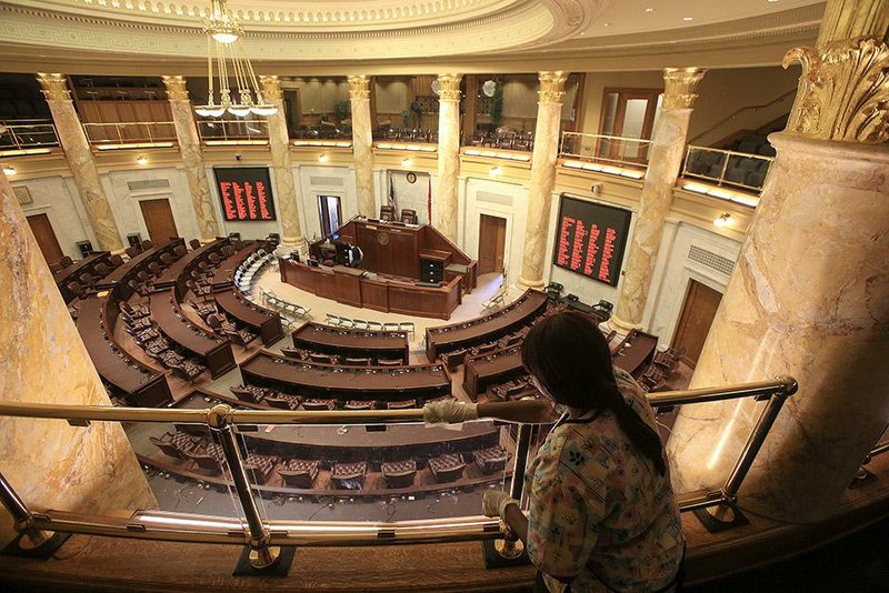 Joyce Bryant polishes the brass railing on the gallery above the House chamber Thursday at the state Capitol.