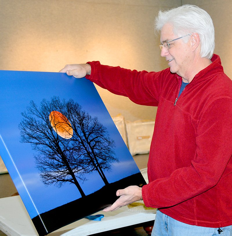 Janelle Jessen/Herald-Leader Charles Peer, director of the John Brown University gallery, held a photo of the recent blood moon by Tim Ernst. Peer was unpacking and hanging Ernst&#8217;s work inside the gallery in preparation for his exhibit, which will open on Jan. 20.