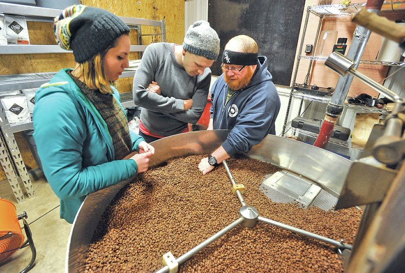 NWA DEMOCRAT-GAZETTE/Michael Woods &#8226; @NWAMICHAELW Jon Allen, center, owner of Onyx Coffee Lab, works with his head roaster Mark Michaelson, right, and assistant roaster Kendel Trout as the check the quality of a batch of roasted coffee beans Thursday evening at their roasting facility in Springdale.