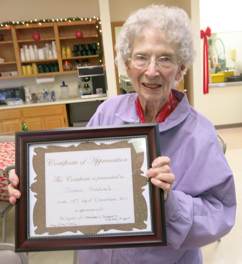 Photo by Susan Holland Jeanne Hubbard, of Gravette, is shown here with the plaque she received at the Billy V. Hall Senior Activity and Wellness Center&#8217;s annual Christmas dinner. Mary Kay Kelley, Center director, presented the plaque on behalf of the Center in appreciation for Jeanne&#8217;s 30 years of attendance, service and monetary support. Jeanne and her husband, El, began attending the Center years ago while it was still located in Sulphur Springs.
