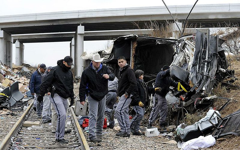 Investigators gather at the site where a prison transport bus crashed into a freight train Wednesday in Penwell, Texas. 