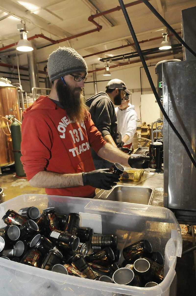 Andy Coates (left) Brant Bishop and Travis Lorton fill cans of beer at Ozark Beer Co. The company can now fill about 10 cans a minute, but will soon have equipment that can fill 27 cans a minute. 