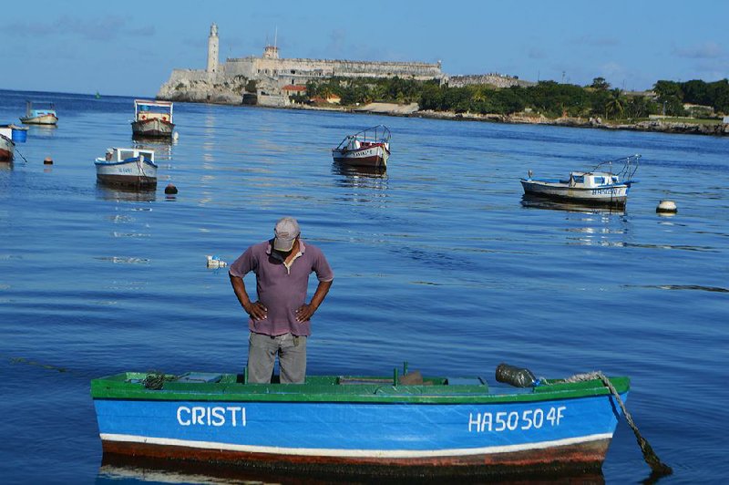 A fisherman stands in his boat in the Havana harbor.  