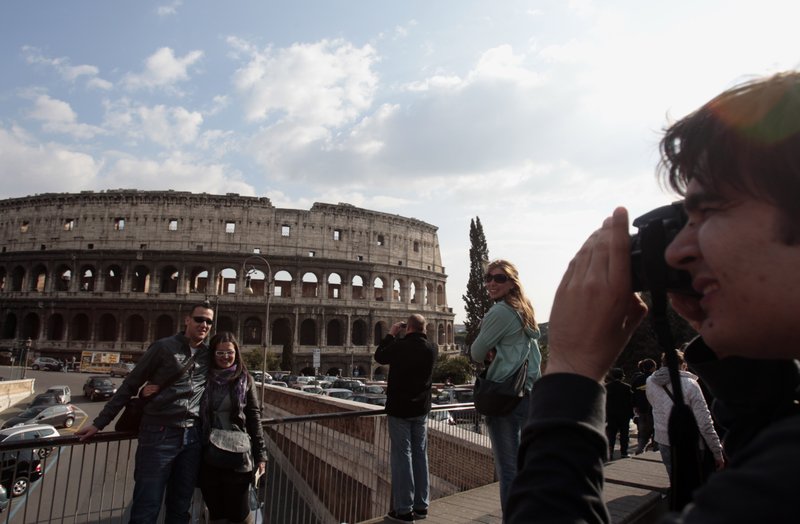 In this Tuesday, March 22, 2011 file photo, tourists take pictures in front of Rome's ancient Colosseum. A strong U.S. dollar is making world travel cheaper for Americans in 2015.