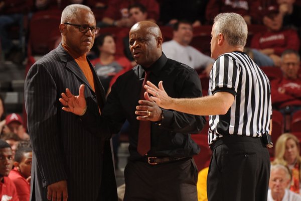 Arkansas coach Mike Anderson, center, and associate coach Melvin Watkins of Arkansas speak to a game official against Mississippi during the second half of play Saturday, Jan. 17, 2015, in Bud Walton Arena in Fayetteville.