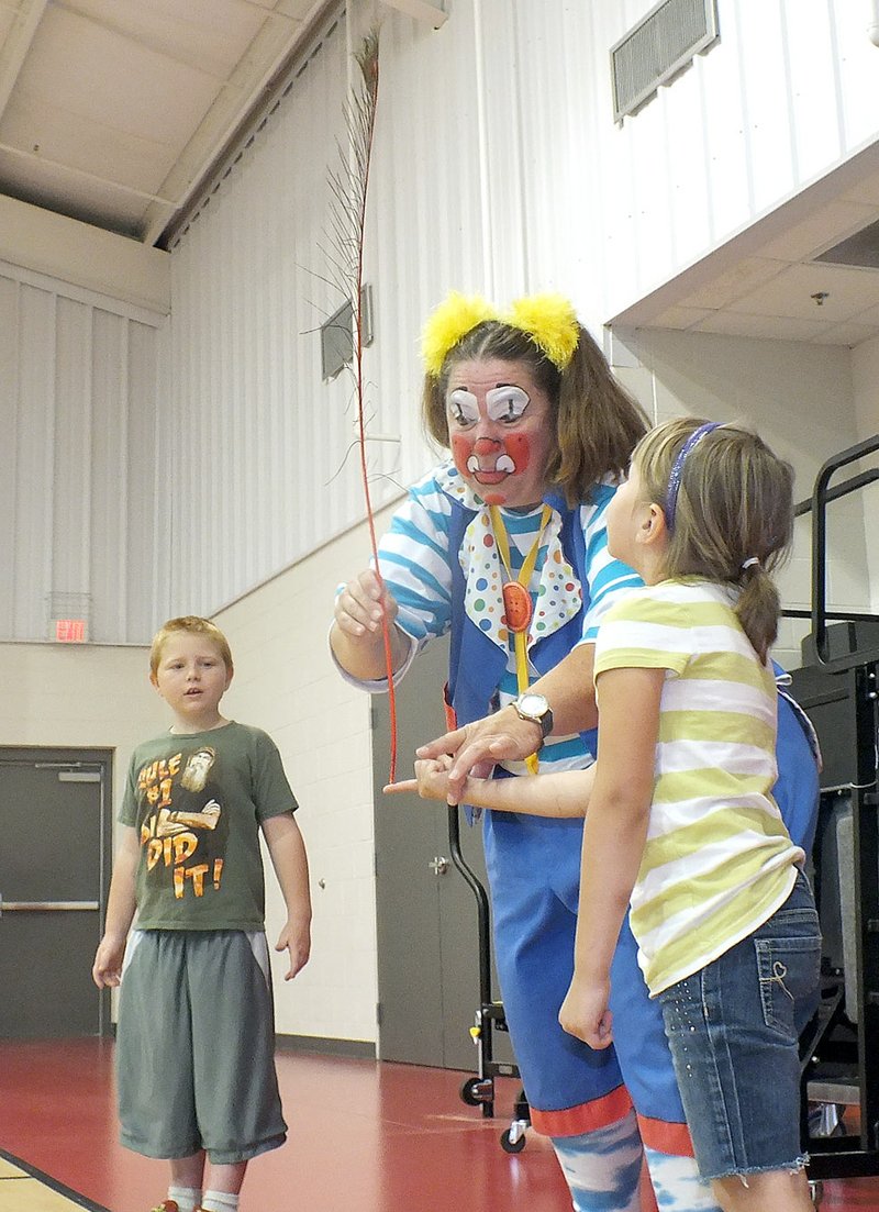Caleb White and Alexis Morrison learned to balance &#8220;Macaroni,&#8221; a peacock feather, on their fingers with a little instruction from Skeeter the Clown, who visited Pea Ridge Primary School this year prior to the Culpepper & Merriweather Circus being in town Wednesday, Sept. 10, at the old Blackhawk Stadium. The circus was sponsored by the Pea Ridge Optimist Club and Lions Club.