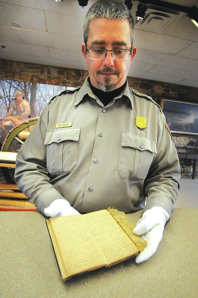 Staff photograph by Spencer Tirey Troy Banzhaf, supervisory park ranger at Pea Ridge National Military Park, shows a diary donated to the park that has a description of the battle there. The diary belonged to Private William Vaughan with the Seventh Division of the Missouri State Guard. See next week&#8217;s TIMES for the rest of the story.