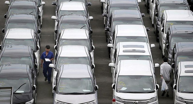 A man checks Toyota cars parked at Yokohama port, near Tokyo, in June before loading them onto a cargo ship for export. 