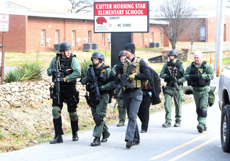 Members of the Garland County sheriff's office Tactical Response Team move down Spring Street near Cutter Morning Star Elementary School Friday, January 23, 2015. A man driving a pick-up truck had some kind of encounter with a deputy then fled on foot prompting a multi-agency manhunt. 