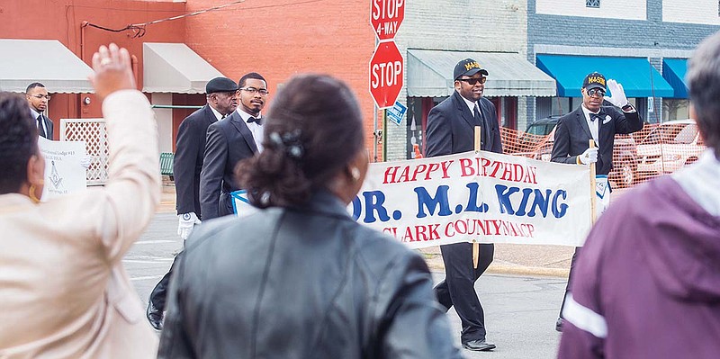 Spectators wave to the crowd walking down main street in Arkadelphia for the celebration of Martin Luther King Jr. Day with a march that ended at the court building.