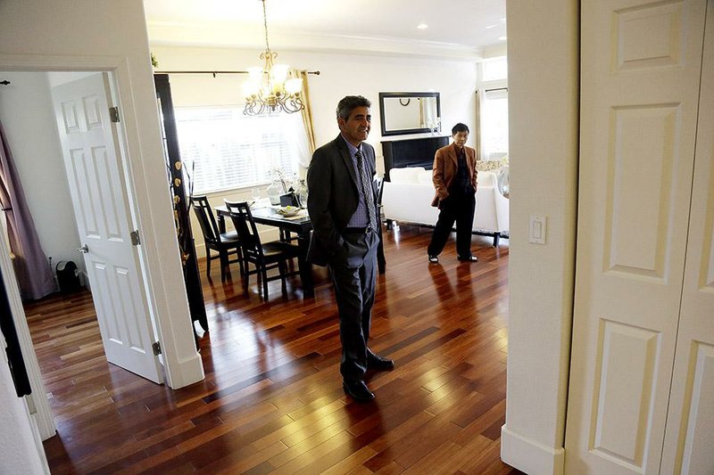 In this Jan. 8, 2015 photo, real estate agent Sam Golkar, left, tours a home being sold by fellow agent Frank Ruan, right, in Cupertino, Calif. The National Association of Realtors reports on sales of existing homes in December on Friday, Jan. 23, 2015. (AP Photo/Marcio Jose Sanchez)