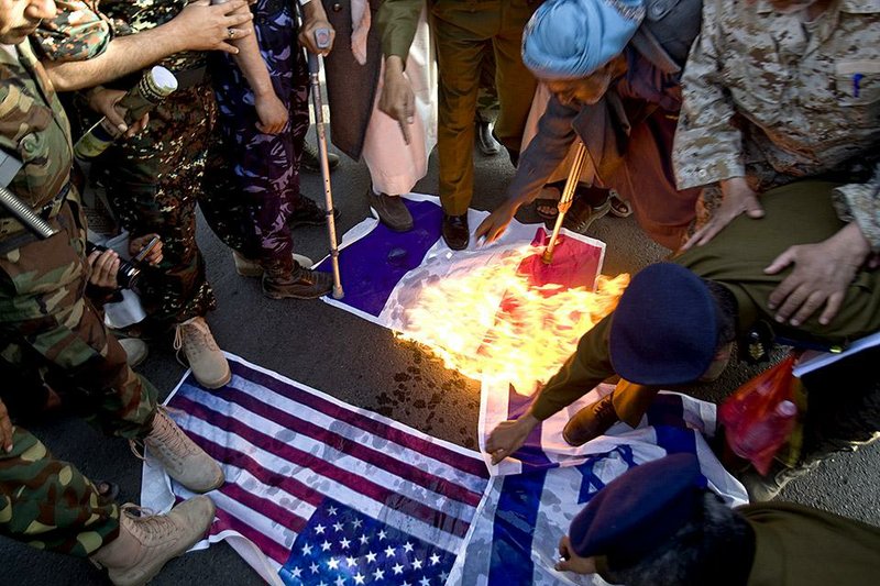 Yemeni protesters burn representations of French, American and Israeli flags during a demonstration to show their support for Houthi Shiite rebels in Sanaa, Yemen, Friday, Jan. 23, 2015. Thousands of protesters demonstrated Friday across Yemen, some supporting the Shiite rebels who seized the capital and others demanding the country's south secede after the nation's president and Cabinet resigned. (AP Photo/Hani Mohammed)