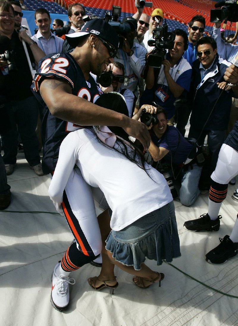 FILE- In this Jan. 30, 2007, file photo, Ines Gomez Mont tries to pick up Chicago Bears safety Tyler Everett during media football day at Dolphin Stadium in Miami. More than 5,500 journalists, psuedo-journalists and other credentialed “media” are expected to gather for Tuesday, Jan. 27, 2015, Media Day at the US Airways Center. (AP Photo/Mike Conroy, File)
