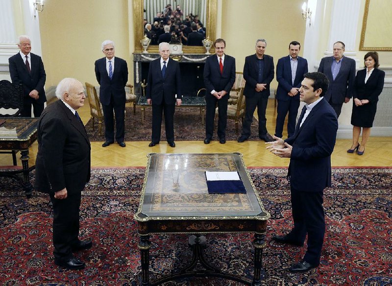 Greece's Prime Minister Alexis Tsipras, right, takes a secular oath to the Greek President Karolos Papoulias at the Presidential Palace in Athens, Monday, Jan. 26, 2015. Radical left leader Alexis Tsipras has been sworn in as Greece's new prime minister, becoming the youngest man to hold the post in 150 years. The 40-year-old broke with tradition and took a secular oath rather than the Greek Orthodox religious ceremony with which prime ministers are usually sworn in.(AP Photo/Thanassis Stavrakis)