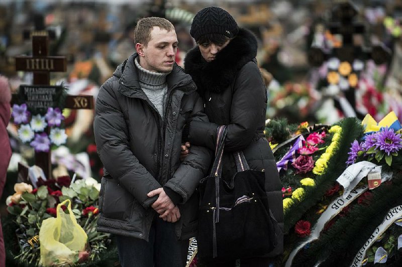 Relatives of Alexander Demyanenko, a victim of Saturday's shelling, stand near a grave during funerals in Mariupol, Ukraine, on Monday Jan. 26, 2015. At least 5,100 people have been killed in eastern Ukraine since fighting began in April, but violence this week was the most intense since a cease-fire deal was signed in September. (AP Photo/Evgeniy Maloletka)