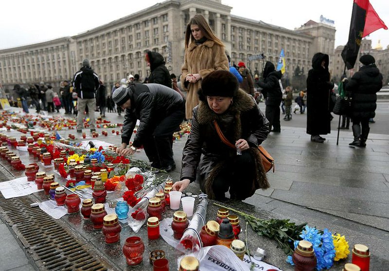 A woman lights a candle on Independence Square in Kiev, Ukraine, Sunday, Jan. 25, 2015 for the victims of a rocket attack on the coastal city of Mariupol. Indiscriminate rocket fire slammed into a market, schools, homes and shops Saturday in Ukraine's southeastern city of Mariupol, killing at least 30 people, authorities said. The Ukrainian president called the blitz a terrorist attack and NATO and the U.S. demanded that Russia stop supporting the rebels. (AP Photo/Sergei Chuzavkov)