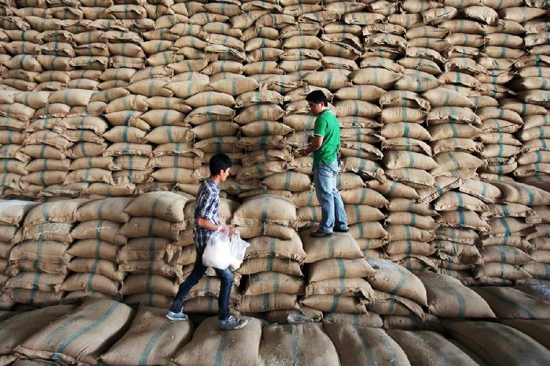 Prospective buyers take samples of rice from sacks in a warehouse during a pre-auction inspection Monday in Chock Chai, Thailand. The government plans to auction more than 1 million tons of rice Thursday that was bought by the government to help farmers. 