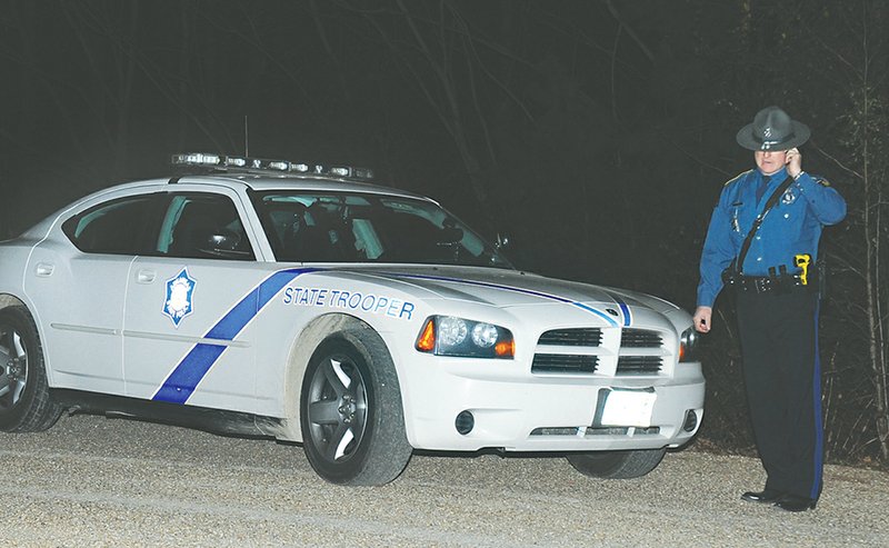 The Sentinel-Record/Mara Kuhn IN CUSTODY: Arkansas State Police Trooper Brandon Cook works a scene on Baywood Trail off Hamilton Dairy Road on Tuesday after pursuing and capturing a person of interest who has been sought since Friday.