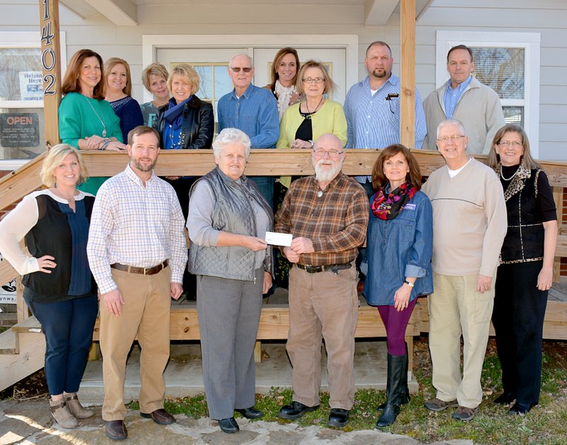 Janelle Jessen/Siloam Sunday The Siloam Springs Council of Realtors presented Genesis House with a $2,500 donation on Wednesday afternoon. Sue Truitt, treasurer for the Siloam Springs Council of Realtors, is pictured presenting the check to Gary Baird, Genesis House executive director, as other Realtors and Genesis House board members look on.