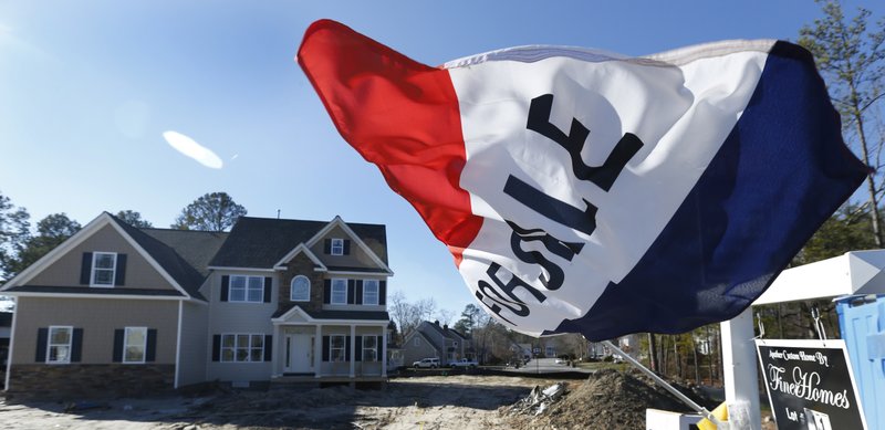 In this Thursday, Jan. 8, 2015 photo, a flag flaps in the breeze in front of a new home for sale in Richmond, Va. The Commerce Department reports on sales of new homes for December on Tuesday, Jan. 27, 2015. 