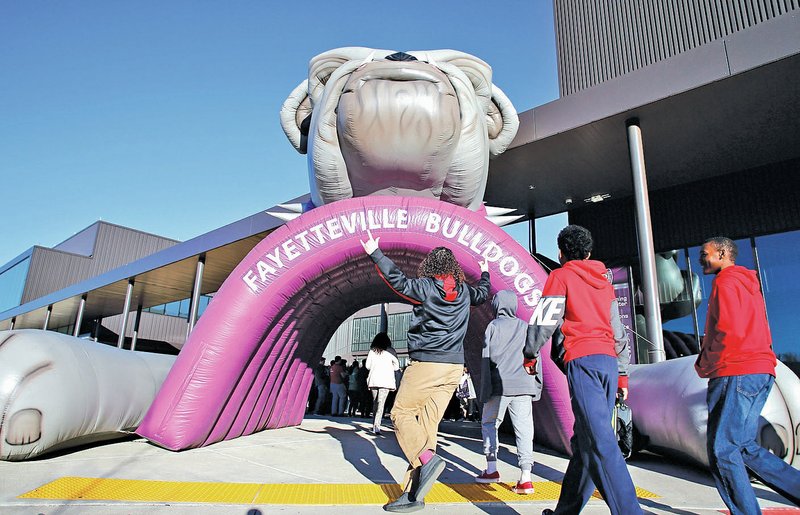 NWA Democrat-Gazette/DAVID GOTTSCHALK Eighth-graders are met Tuesday by a large inflatable tunnel as they arrive at Fayetteville High School. The district is beginning to transition the students to become the first freshmen class at the high school. The students were met by the marching band, color guard and cheerleaders before spending the day in orientation, which included an introduction to Advance Placement classes, introduction to the varying schedules and lunch in the cafeteria.